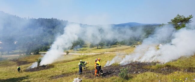 Brandweerlieden bestrijden smeulende bermbrand in droog heidegebied