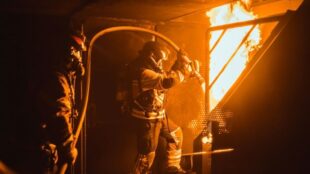 Brandweerlieden bestrijden een felle brand in een metalen ruimte